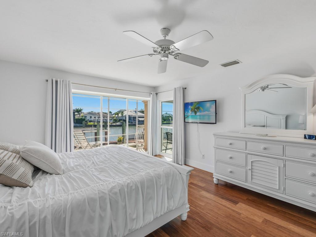 Bedroom with dark wood-style floors, a ceiling fan, and access to outside