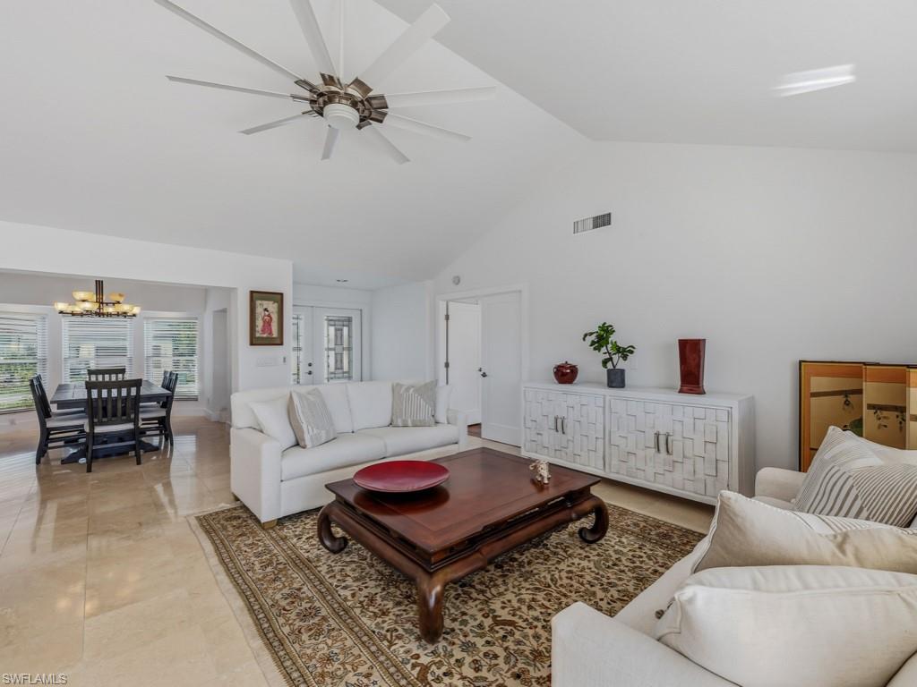 Living room with ceiling fan, a chandelier, and high vaulted ceiling