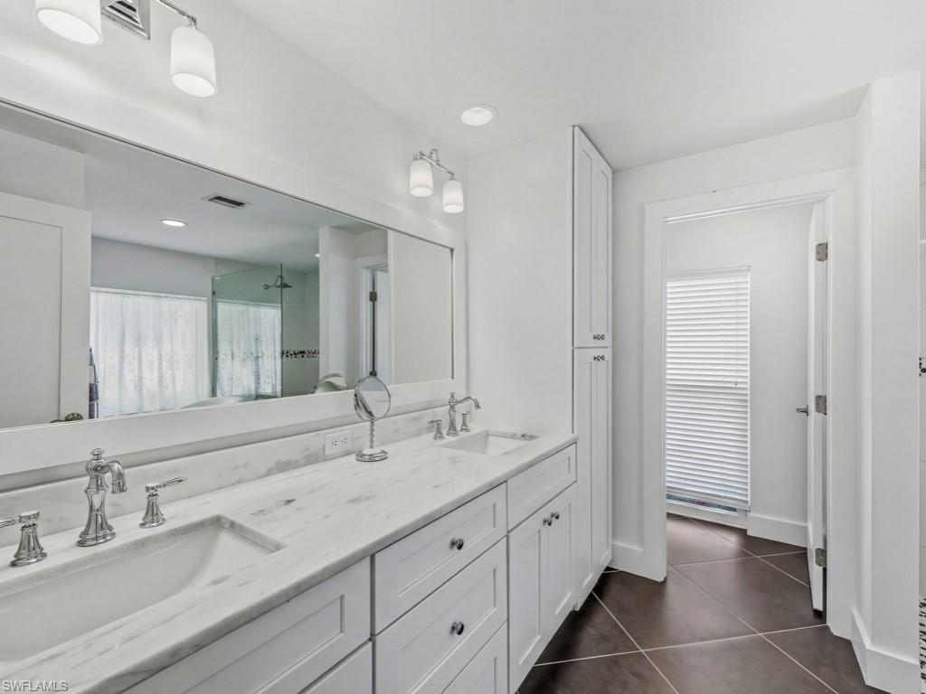 Full bath with a stall shower, double vanity, dark tile patterned floors, and recessed lighting
