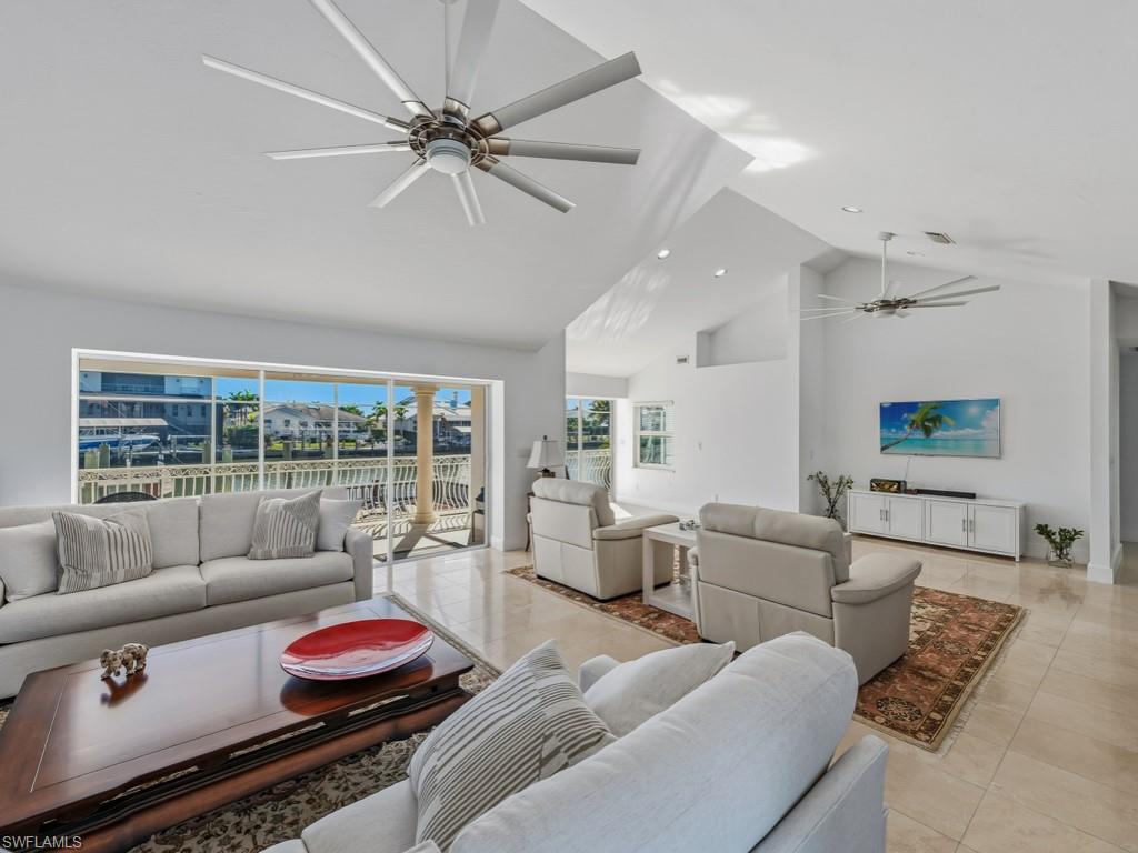 Tiled living area featuring a ceiling fan and high vaulted ceiling