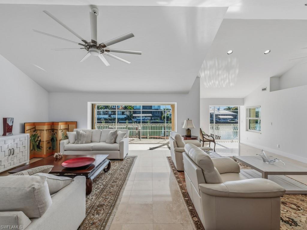 Living area featuring plenty of natural light, light tile patterned flooring, a ceiling fan, and high vaulted ceiling