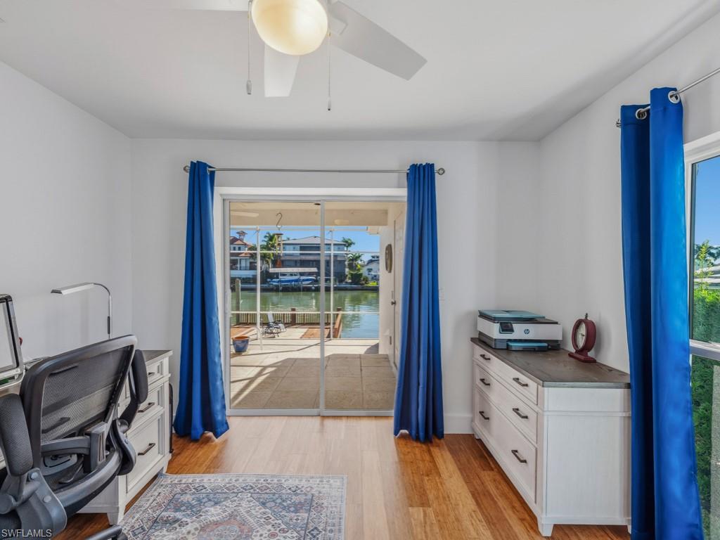 Office featuring a water view, light wood-style flooring, and a ceiling fan
