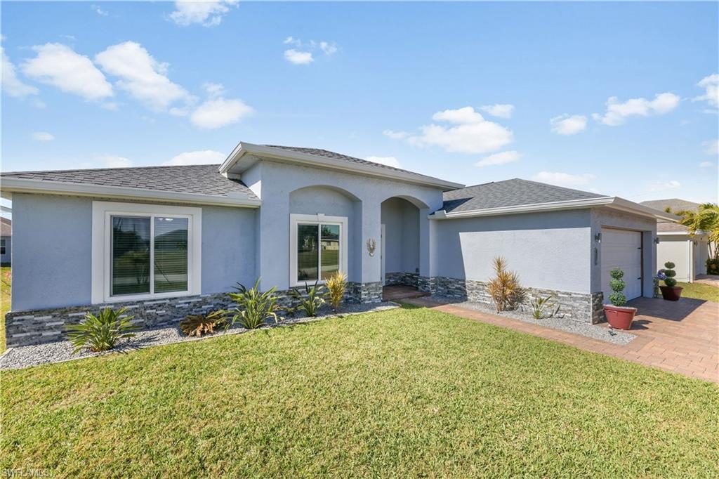 View of front of house featuring stone siding, a garage, stucco siding, and a front yard