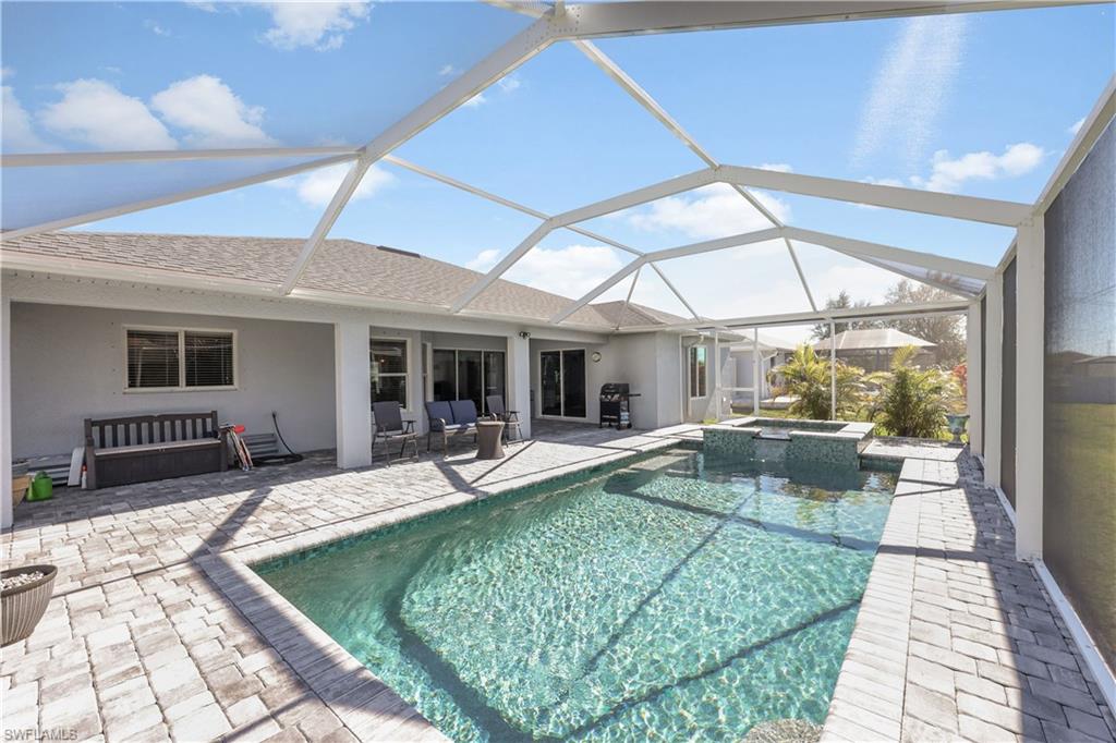 View of pool with a sunroom, a patio, a lanai, a pool with connected hot tub, and outdoor lounge area