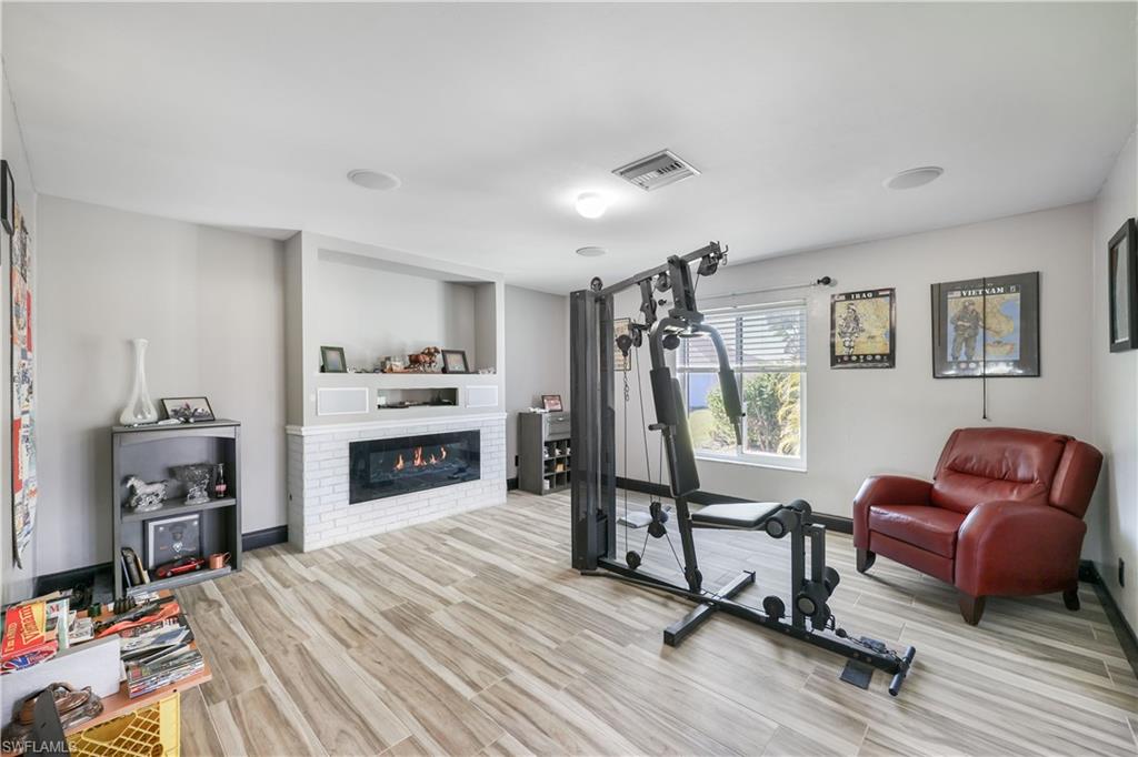 Exercise room featuring light wood finished floors and a brick fireplace