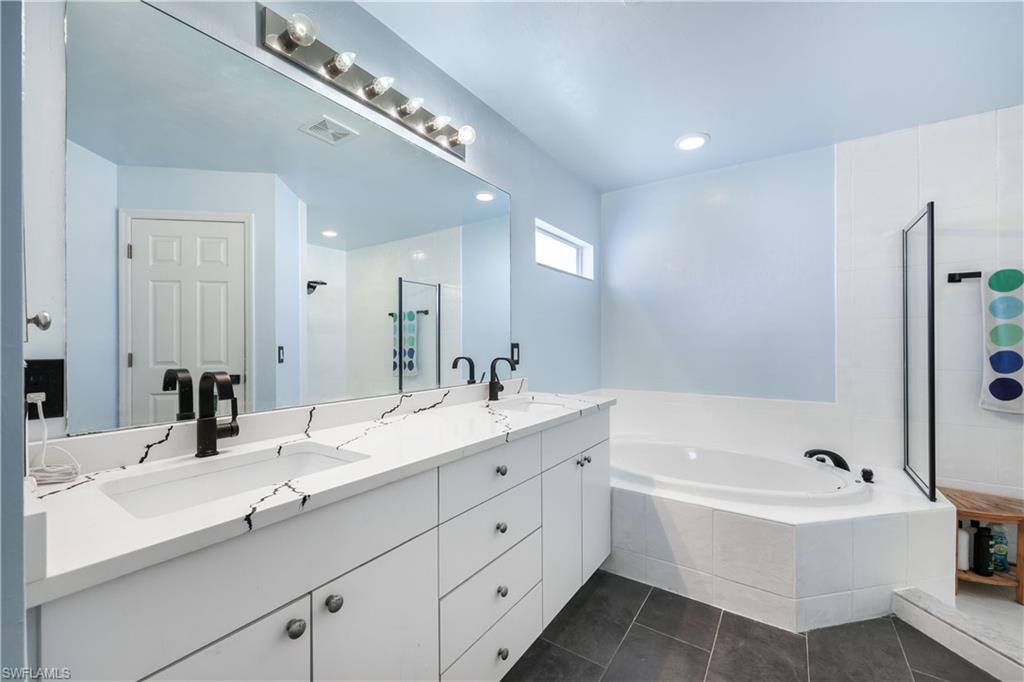 Bathroom with a garden tub, double vanity, dark tile patterned floors, recessed lighting, and walk in shower