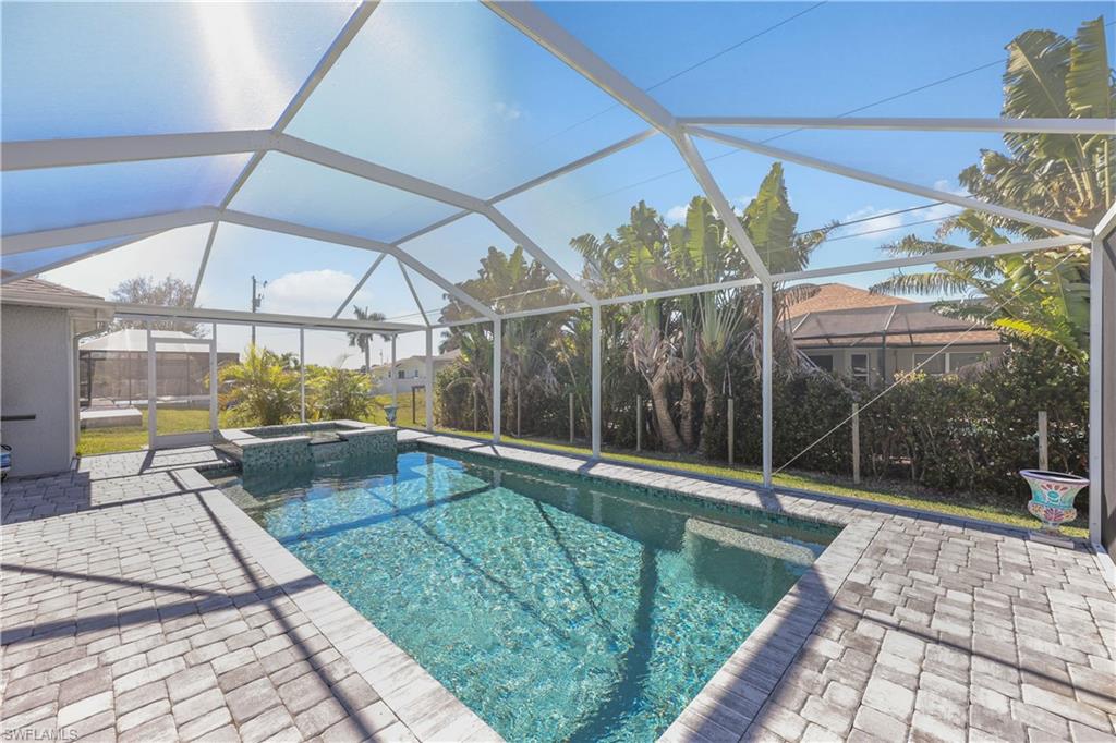 View of pool with a sunroom, glass enclosure, a pool with connected hot tub, and a patio area