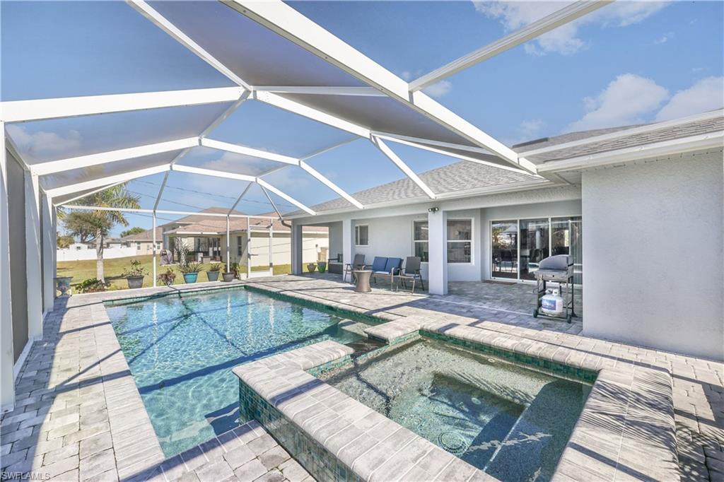 View of pool with a sunroom, a patio area, grilling area, and a pool with connected hot tub