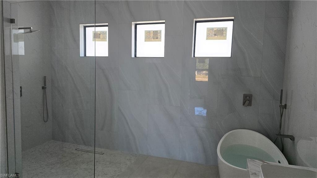 Bathroom featuring a marble finish shower and a freestanding tub