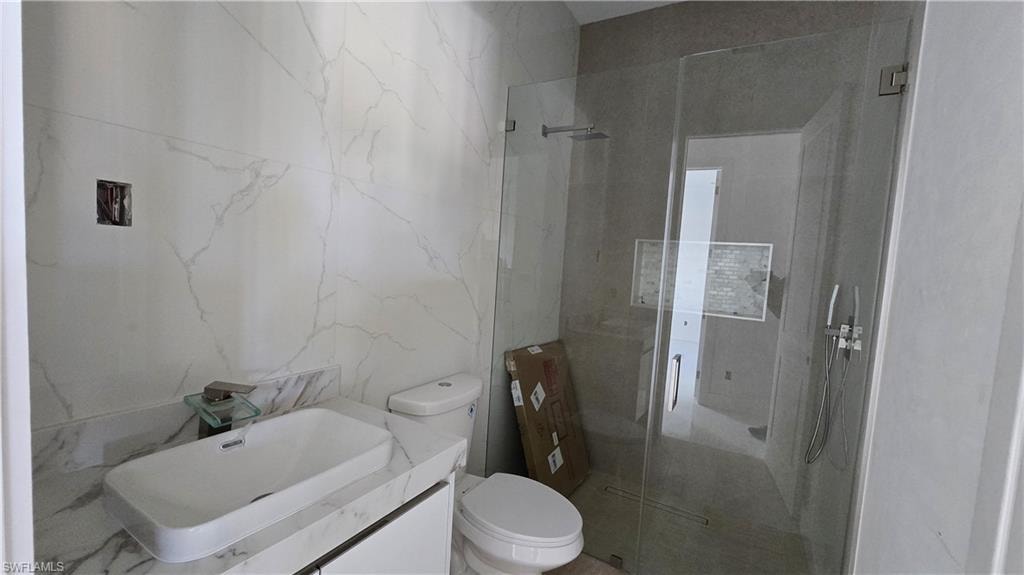 Bathroom with a stall shower, vanity, and tile walls