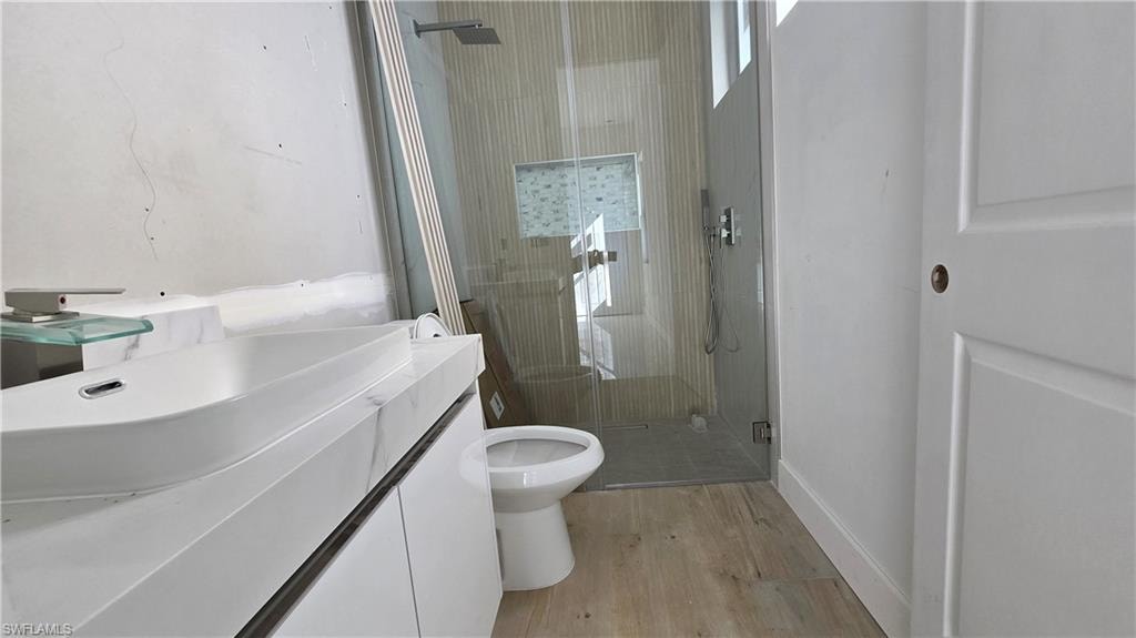 Full bath featuring vanity, a stall shower, and light wood finished floors