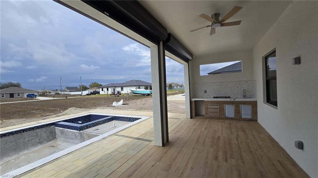 Wooden terrace with an in-ground hot tub, ceiling fan, a residential view, a patio, and area for grilling