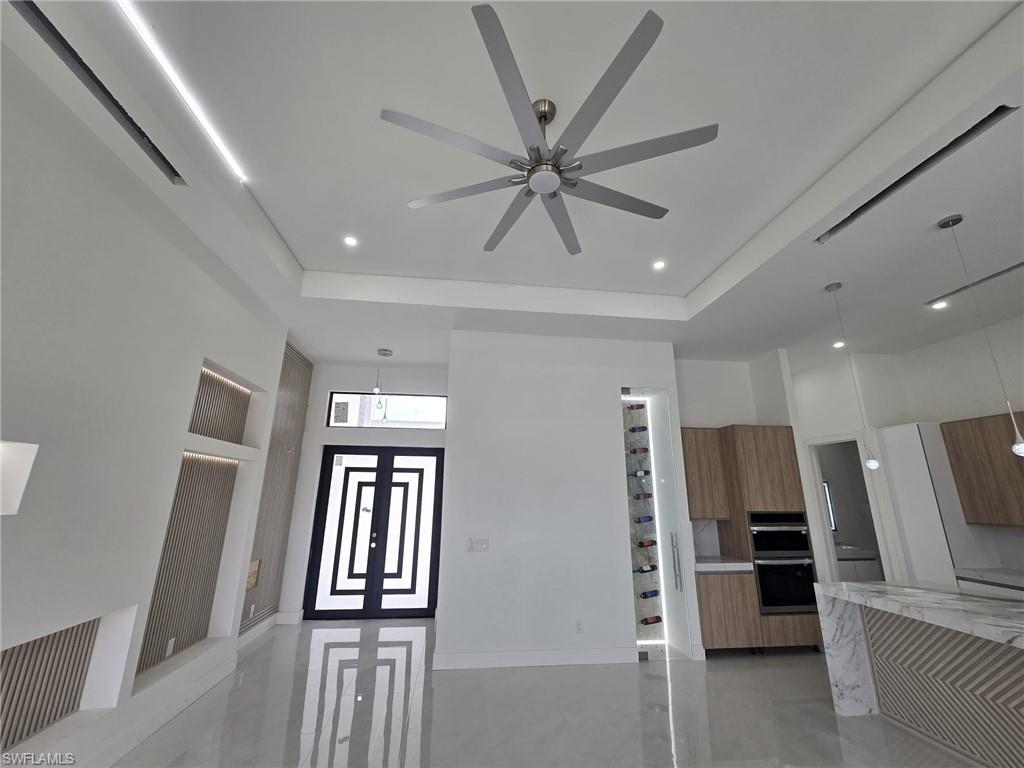 Kitchen with modern cabinets, decorative light fixtures, light stone counters, wood finish cabinetry, and finished concrete floors