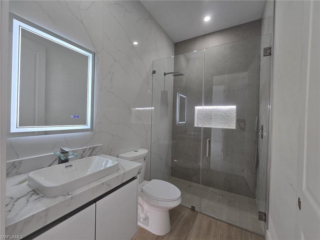 Bathroom with vanity, a marble finish shower, recessed lighting, stone wall, and tile walls