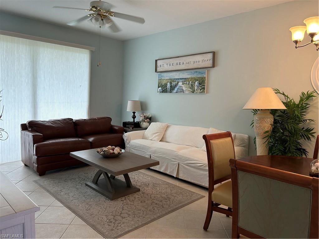 Living area featuring tile flooring, a ceiling fan with integrated lighting, and vertical window treatments