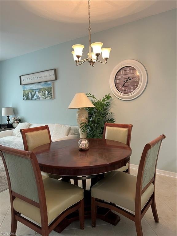 Dining area featuring a central chandelier, light blue wall paint, and tile flooring
