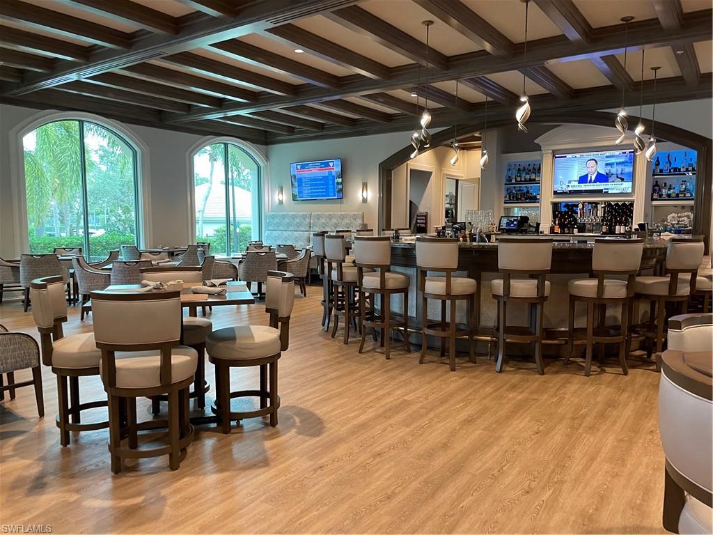 Dining space with coffered ceiling, bar, wood-style flooring, and beamed ceiling
