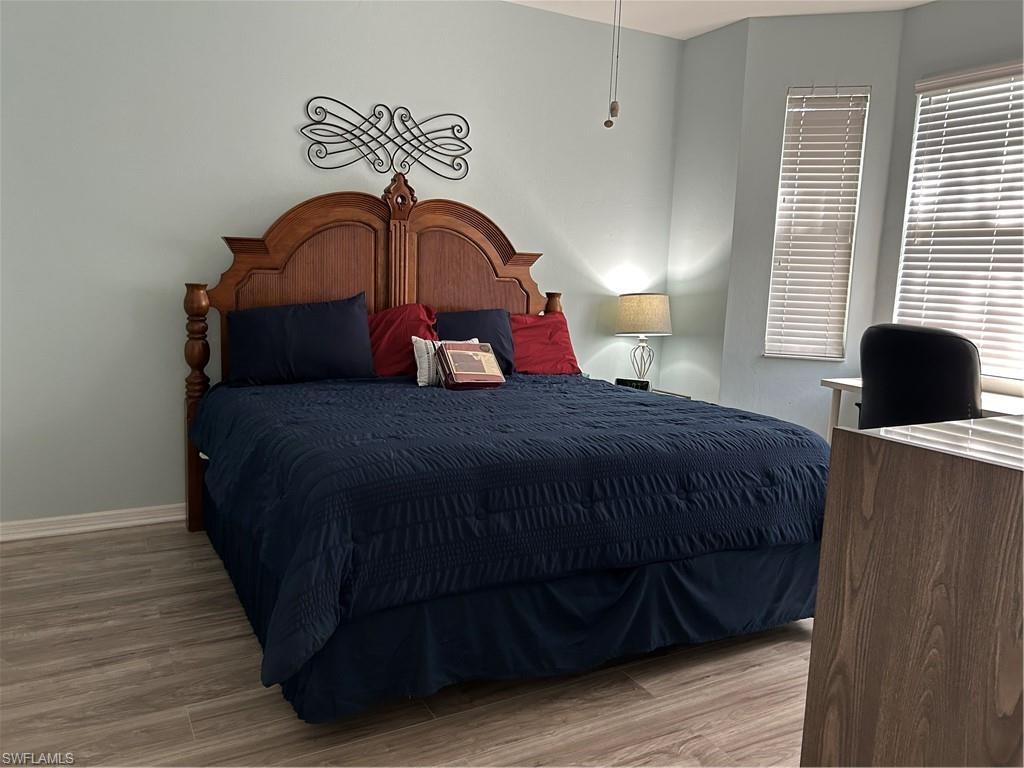Spacious interior room featuring wood-finish flooring, light blue wall paint, and a decorative wall scroll