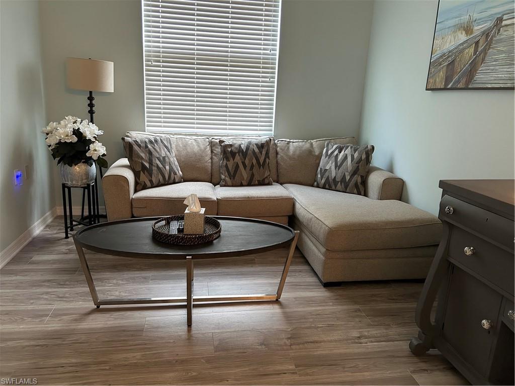Inviting living area featuring wood-finish flooring, light-colored walls, and a window with horizontal blinds