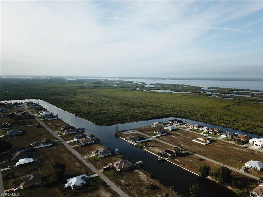 Aerial view of property and surrounding area featuring nearby suburban area and a large body of water