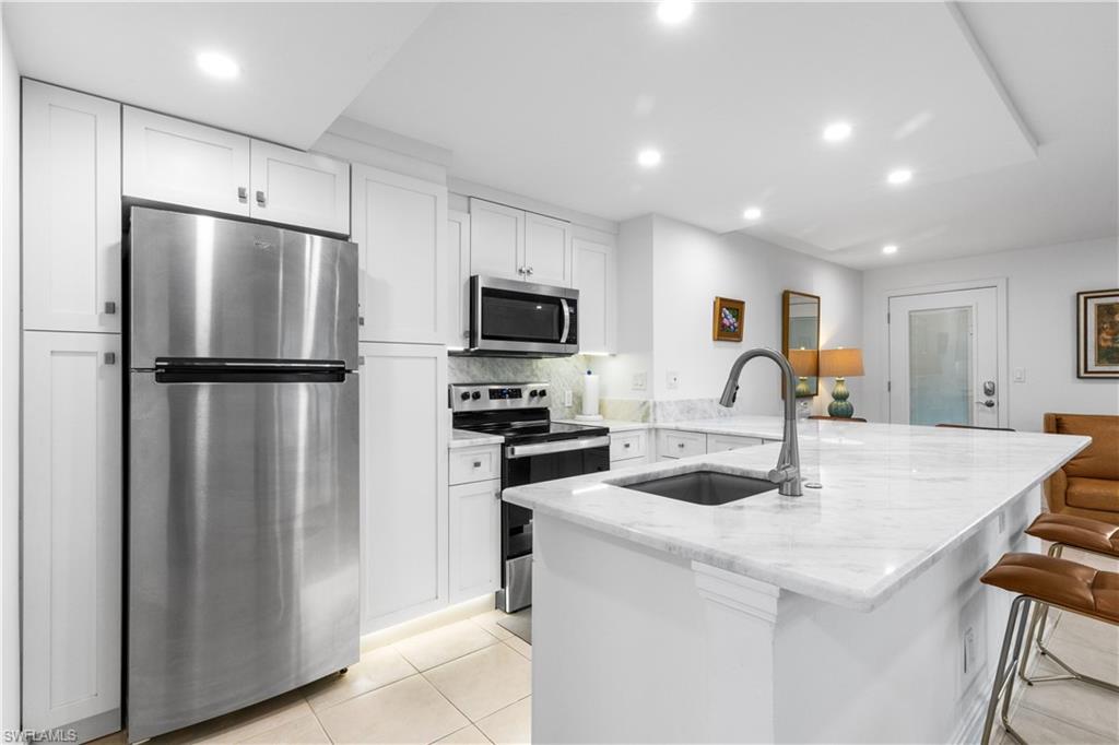 Kitchen has marble countertops, undercounter sink, under cabinet lighting along with stainless steel appliances; refrigerator, stove, microwave, dishwasher, and disposal.
