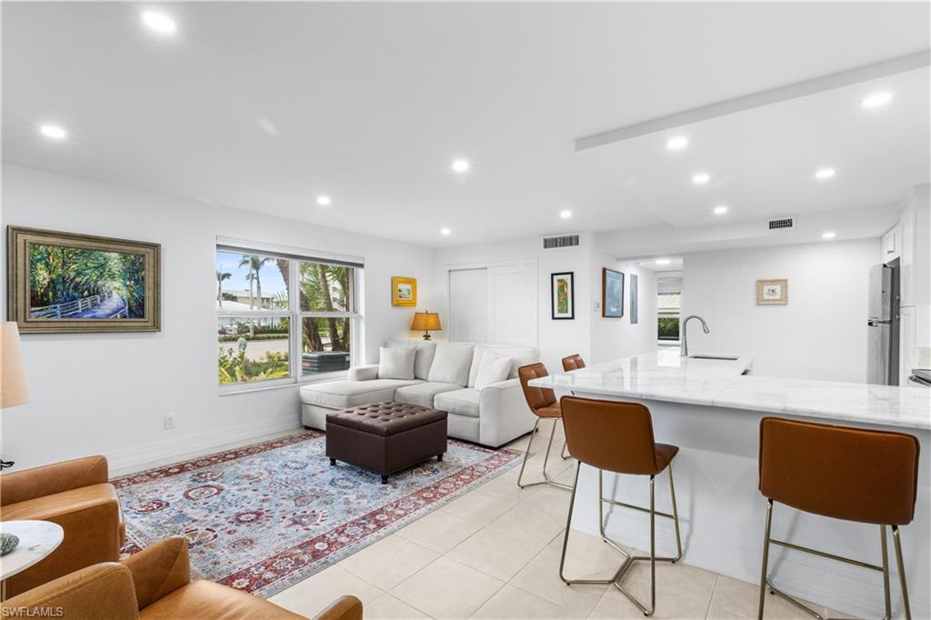 Spacious living room / kitchen area. Laundry is located in closet behind couch.  Furnishings included. Canned lighting and windows make this condo light and bright!  Marble countertops.
