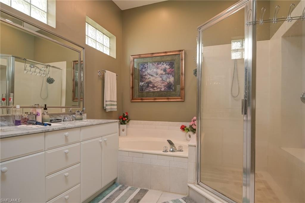 Bathroom featuring double vanity, a garden tub, a shower stall, and light tile patterned floors