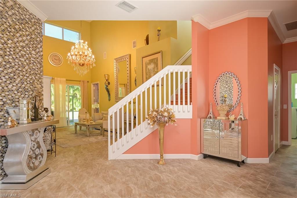 Foyer with stairway, ornamental molding, healthy amount of natural light, a towering ceiling, and a chandelier