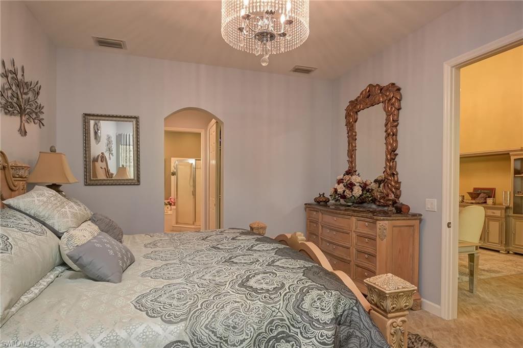 Bedroom featuring arched walkways, a chandelier, and ensuite bath