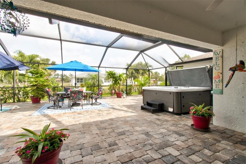 View of patio with glass enclosure, a hot tub, a sunroom, and outdoor dining space