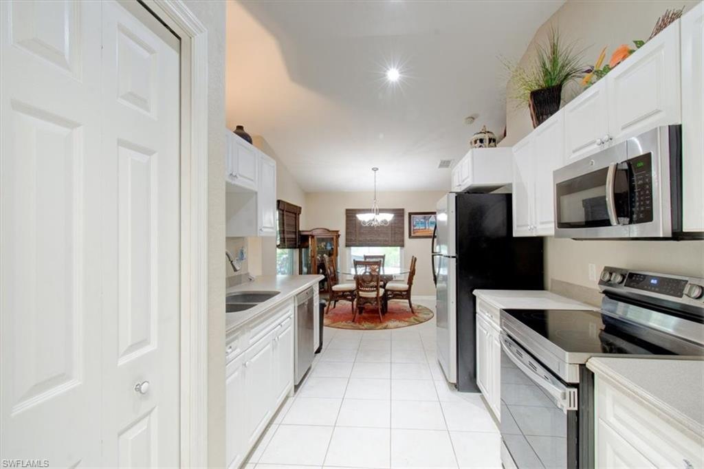 Kitchen with stainless steel appliances, pendant lighting, white cabinets, and light countertops