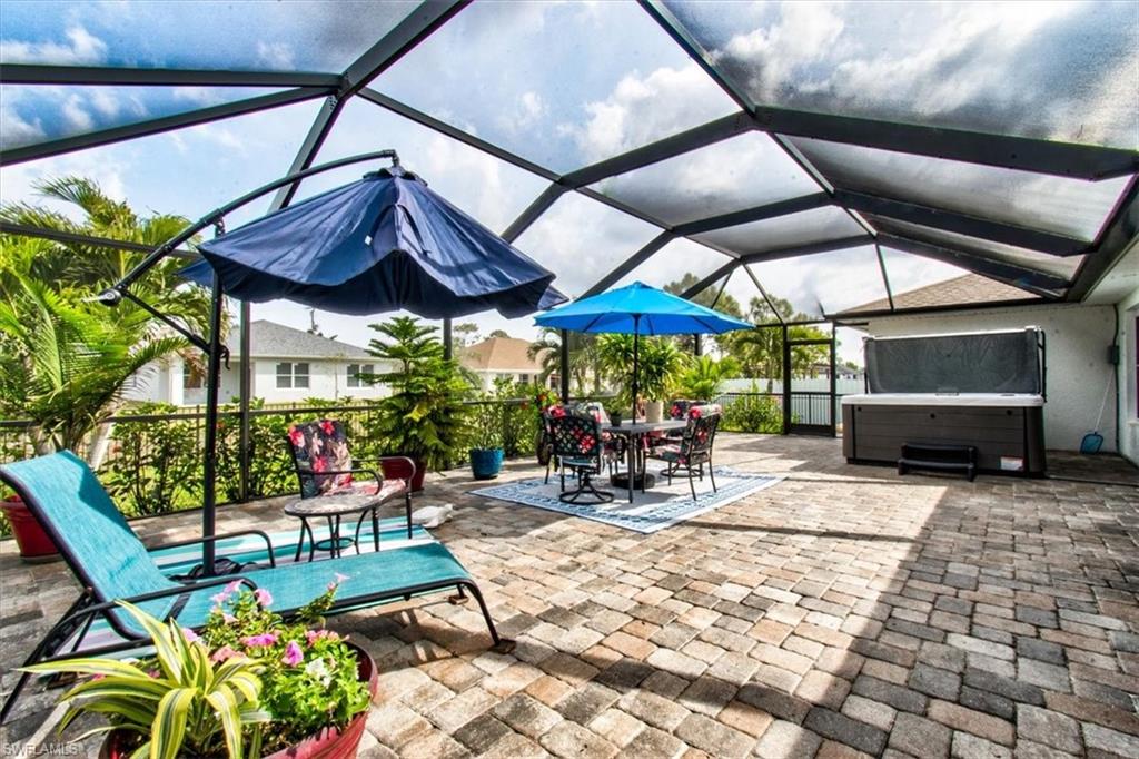 View of patio with a hot tub, a sunroom, glass enclosure, and outdoor dining space