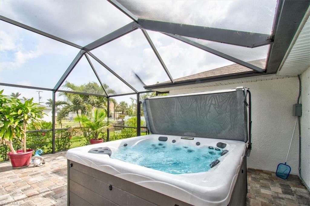 View of patio / terrace with a hot tub, a sunroom, and glass enclosure
