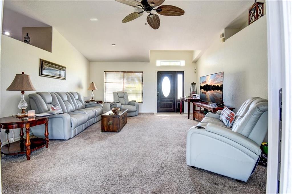 Carpeted living area with ceiling fan and lofted ceiling