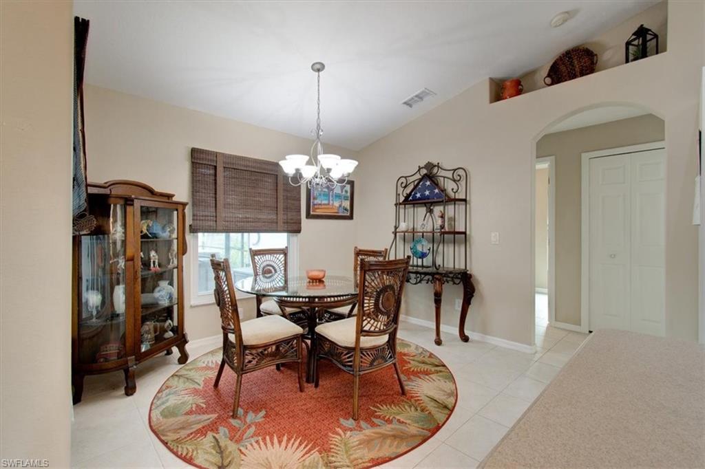Dining space with arched walkways, light tile patterned floors, a chandelier, and vaulted ceiling