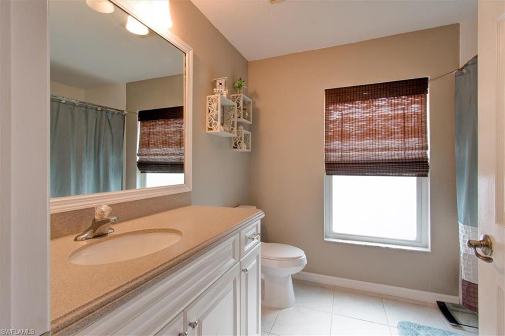 Full bathroom with vanity, light tile patterned floors, a shower with curtain, and plenty of natural light
