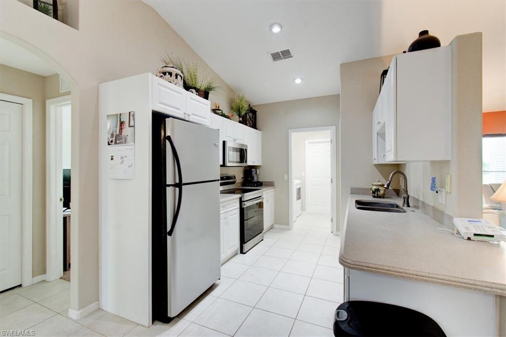 Kitchen with appliances with stainless steel finishes, white cabinets, arched walkways, light countertops, and recessed lighting