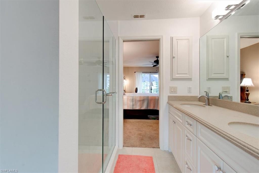 Bathroom with ensuite bathroom, double vanity, light colored carpet, a shower stall, and light tile patterned floors