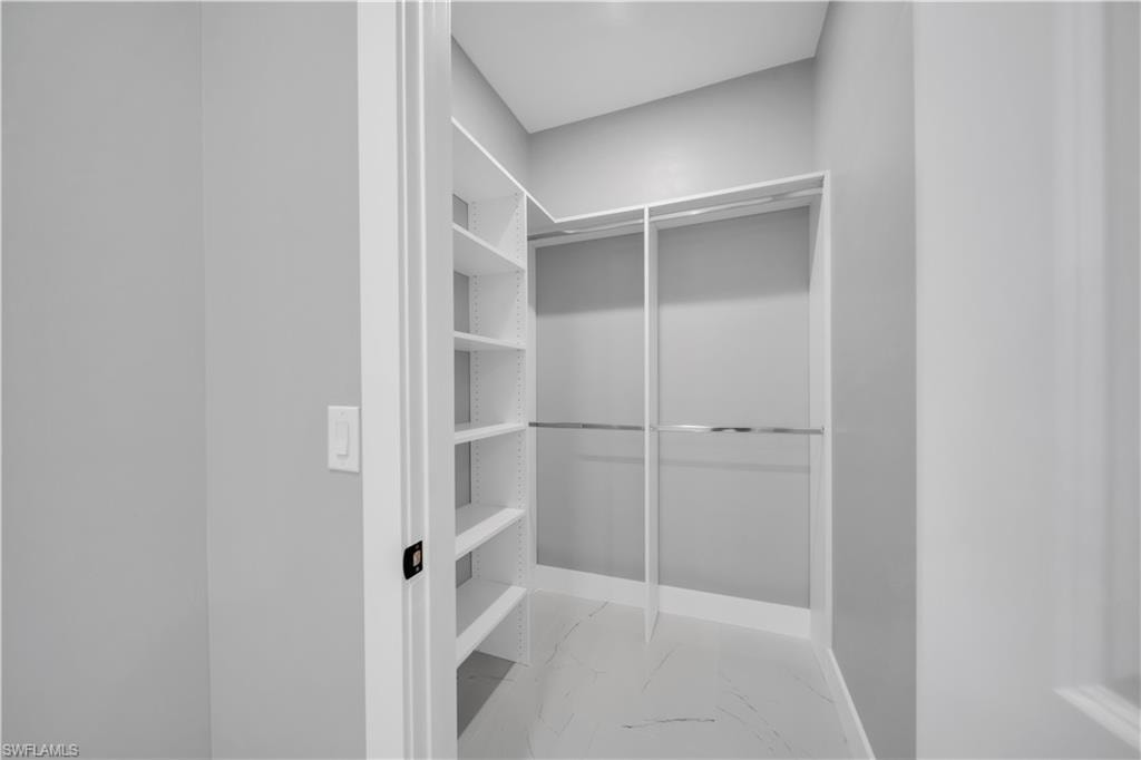 Walk in closet with light marble finish flooring