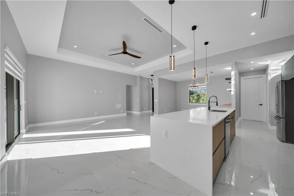 Kitchen with light marble finish floors, decorative light fixtures, light stone countertops, stainless steel appliances, and recessed lighting