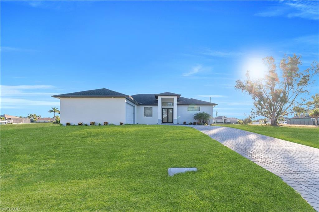 View of front of home with a front yard, decorative driveway, and stucco siding