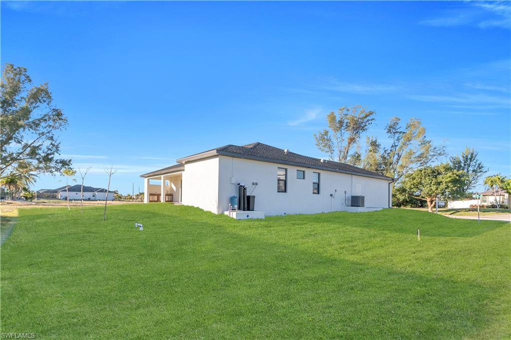 Back of property featuring a lawn and stucco siding