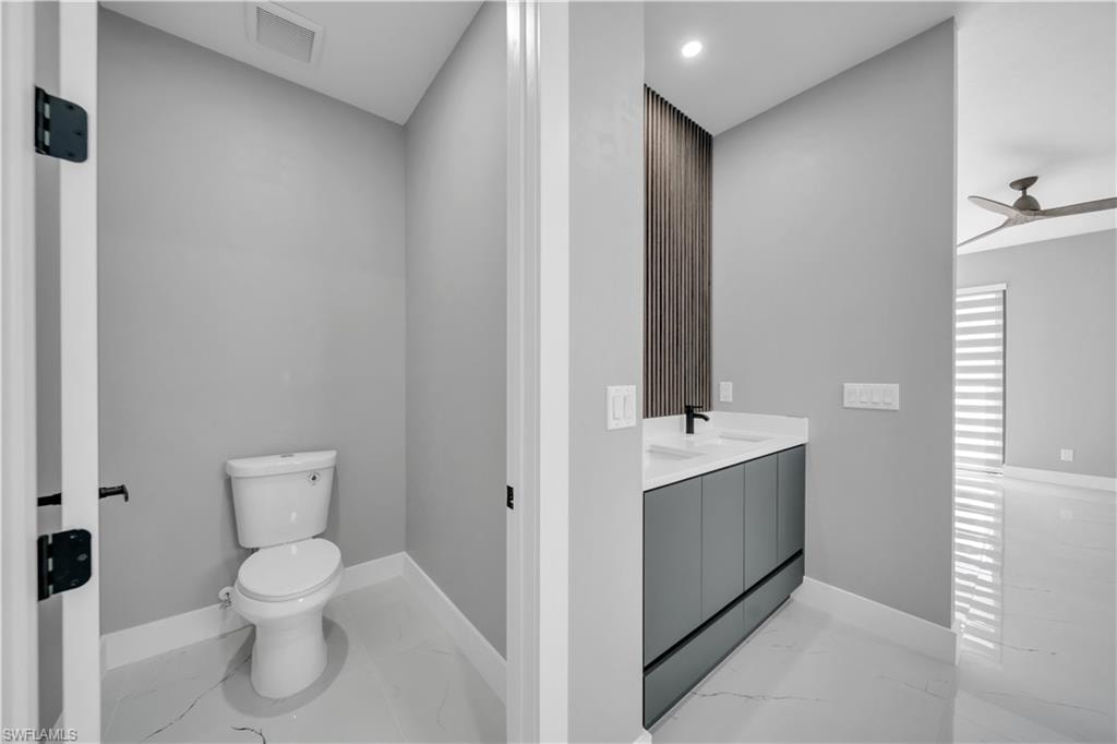 Full bathroom featuring light marble finish floors, a ceiling fan, double vanity, and recessed lighting