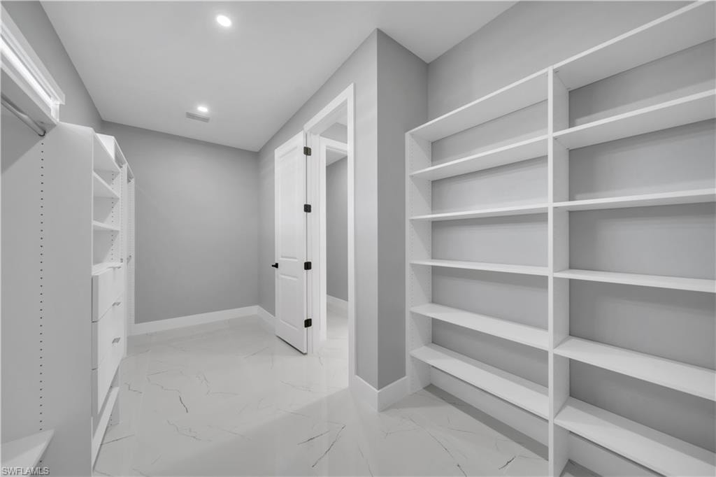Walk in closet with light marble finish floors
