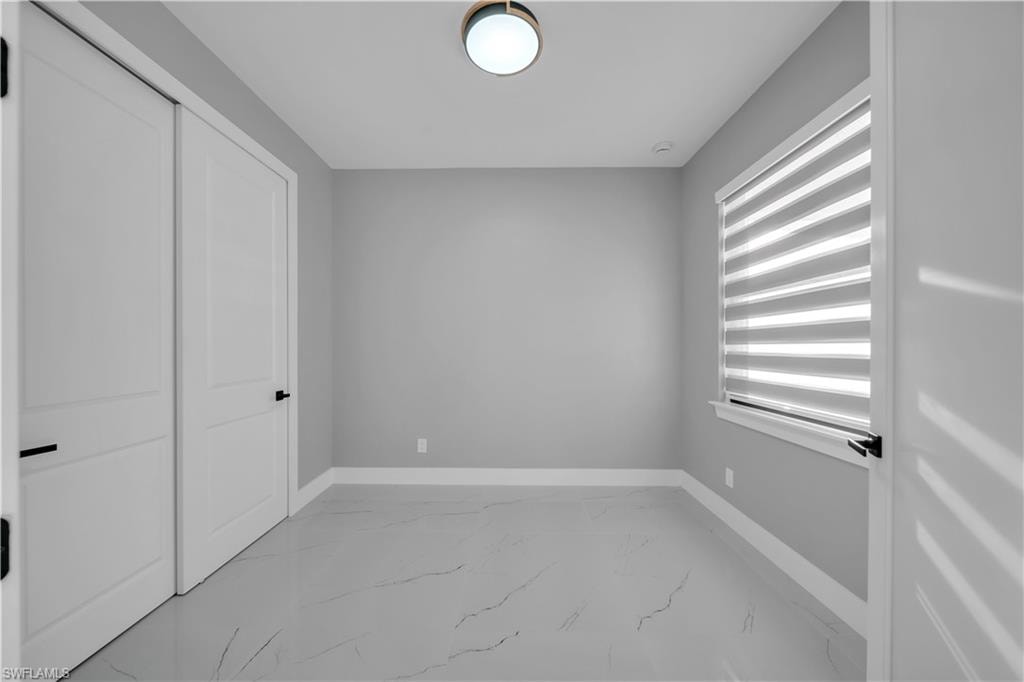 Unfurnished bedroom featuring light marble finish floors and a closet