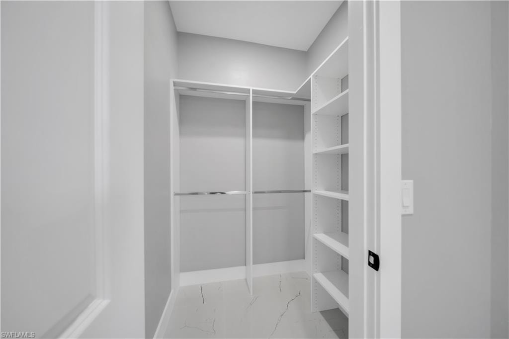 Walk in closet with light marble finish flooring