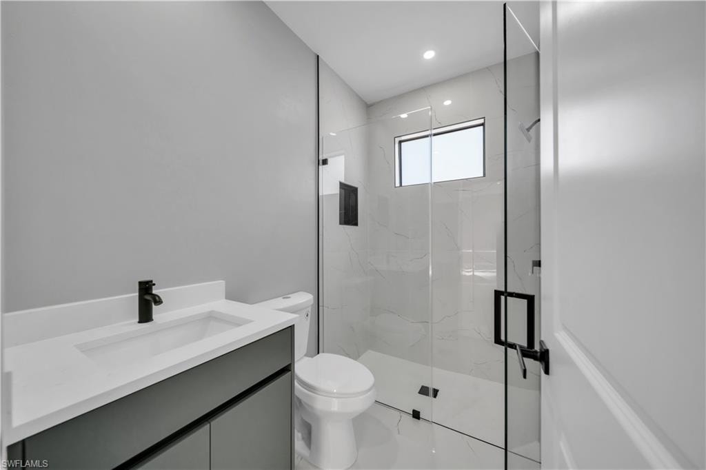 Bathroom with vanity, a marble finish shower, and light marble finish flooring