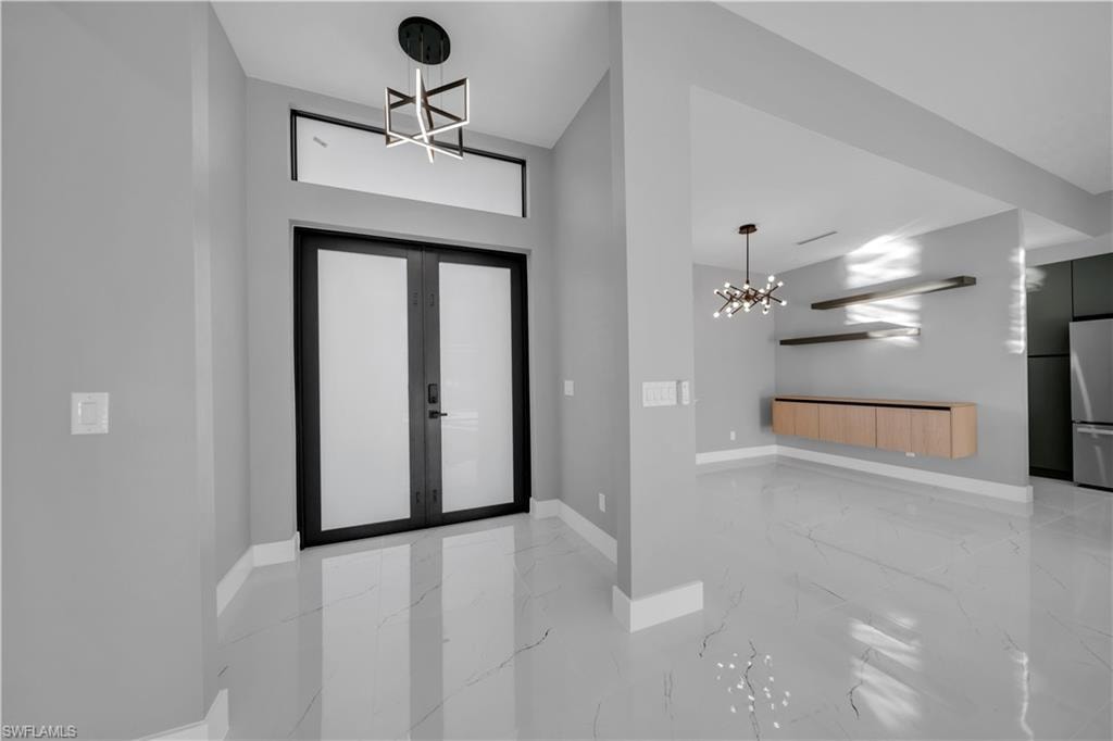 Entryway with a chandelier, light marble finish floors, and french doors