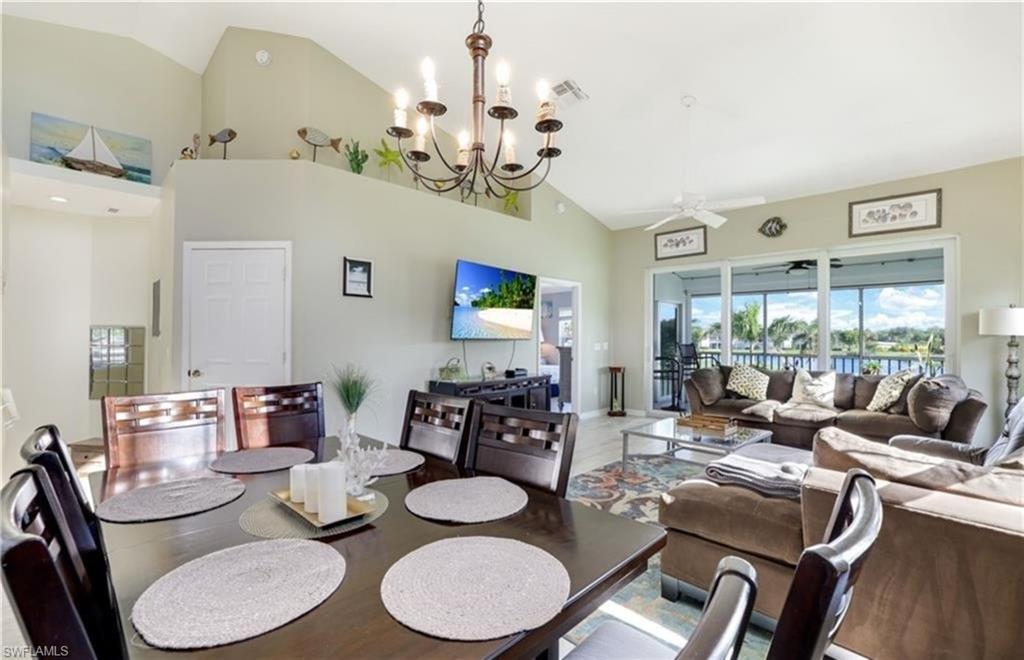 Dining area with ceiling fan, a chandelier, and high vaulted ceiling