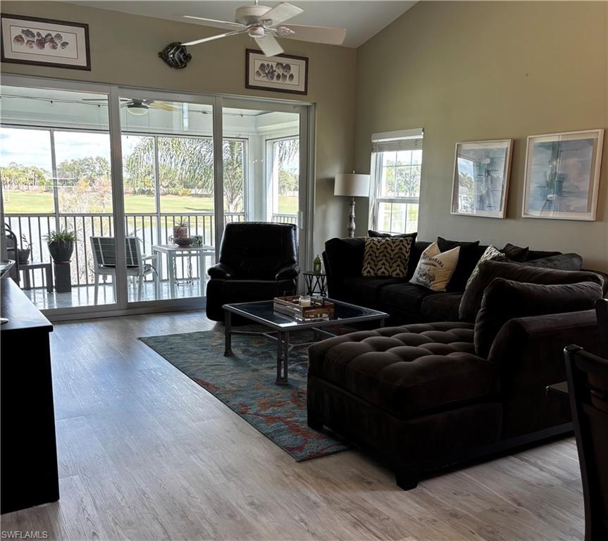 Living area featuring light wood-type flooring, ceiling fan, and high vaulted ceiling